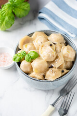 Pelmeni, ravioli, meat stuffed steamed dumplings in a bowl. White marble background