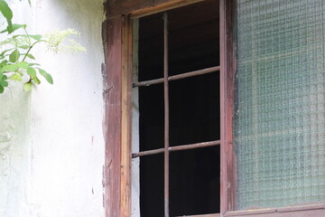 An old white wall with a broken window close up