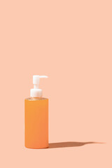 cBottle dispenser  with orange cosmetic gel  on beige background with shadow.Copy space