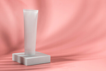 Beauty cocnept. Abstract white cosmetic tube on white podium on pink background with beautiful shadow