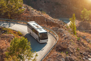 White tourist bus rides along a serpentine road in the rocky mountains. Travel and travel by public...