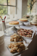 A beautifully arranged wedding dessert table featuring an assortment of pastries and cakes, elegantly presented in a bright and rustic setting.
