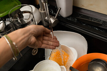 Dirty dishes in the sink with water and a washcloth, cleaning up after meals