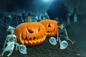 Halloween's decoration with two pumpkins, zombie husbands and skulls, in the cemetery. Halloween's...