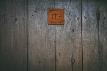 A mysterious wooden antique door with the number 113 on it. Can be used for cinematographic, horror, halloween