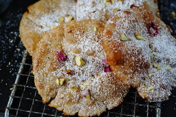 Meethe Chongay or Sweet poori topped with powdered sugar and nuts, selective focus
