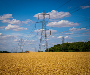 Pylon Power Electricity Electrical Distribution Aerial Cable Running through Countryside Farmer Fields with Blue Sky and White Clouds