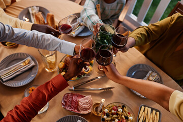 Close up of African American family clinking glasses over dinner table outdoors in cozy evening setting
