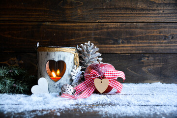 Wintry Christmas decoration with a small lantern, winter apple and cones in the snow in country...