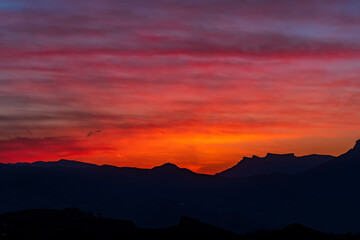 natural background - bright scarlet sunset sky over the silhouettes of mountain peaks