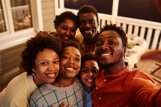 POV of happy African American family taking selfie photo at house terrace in evening