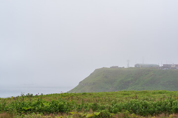 Fototapeta na wymiar foggy cape with a telecommunication point in a gloomy sea