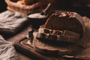 Homemade bread with parchment paper at wood table. Bread on wooden tabletop as baking concept
