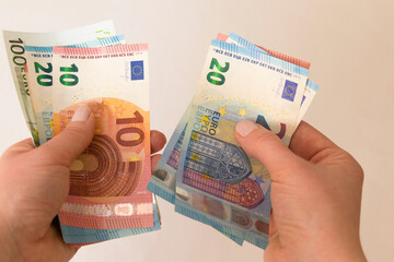 Female hands holding euro banknotes on a grey background.