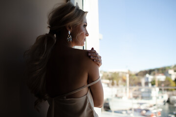 Fototapeta premium Portrait of a beautiful girl with an evening elegant hairstyle and cmokey eyes makeup, a woman dressed in a silk shirt and earrings