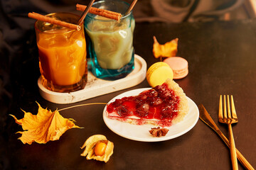 Glasses of pumpkin latte, cinnamon sticks and cherry pie. Seasonal autumn coffee time. Cozy hygge home aesthetic