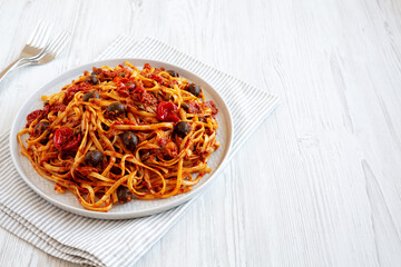 Homemade Tuna Linguine Pasta with Tomatoes, Olives and Capers on a Plate, low angle view. Copy space.