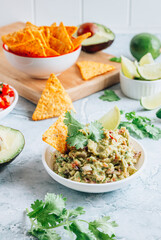 Mexican guacamole sauce and tortilla nachos chips on a gray marble background.