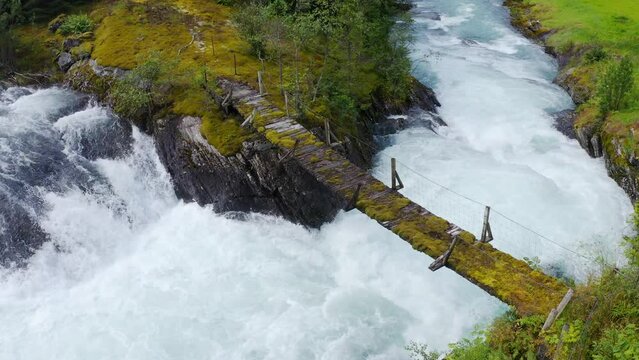 wooden bridge across Lake Lovatnet with a glacial river, view from above. moving aerial