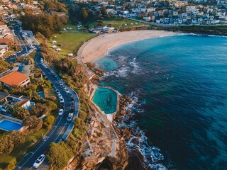 Aerial of Bronte beach with the busy highway and cityscape background - obrazy, fototapety, plakaty