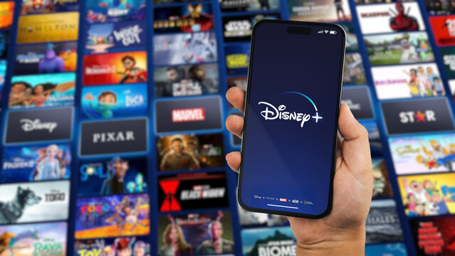 Boy holding a smartphone iPhone 14 Pro with Disney+ (Disney Plus) streaming app app on the screen. Website blurred in the background. Rio de Janeiro, RJ, Brazil. October 2022