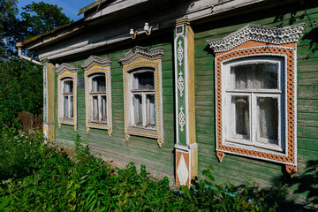 Old wooden painted windows. Carved platbands, closed shutters. Wooden facade of a typical residential building of the early 20th century