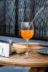 Aperol spritz cocktail served in a big wine glass with ice cubes and a drinking straw