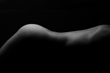 Artistic nude with lighting on bare skin from the back to lower thighs of male model black background