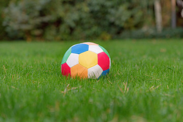 A soccer ball with different colors lies on the green grass.