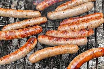 Grilled juicy sausages cooked on a campfire outdoors.