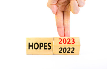 2023 hopes new year symbol. Businessman turns a wooden cube and changes words Hopes 2022 to Hopes 2023. Beautiful white background, copy space. Business 2023 hopes new year concept.