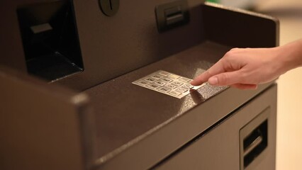 Faceless woman dialing bank card pin at ATM. 