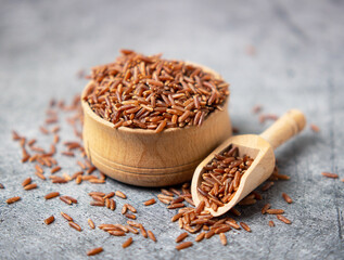 brown rice closeup in a wooden bowl and scoop