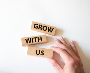 Grow with us symbol. Wooden blocks with words Grow with us. Beautiful white background. Businessman hand. Business and Grow with us concept. Copy space.