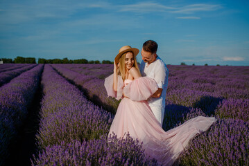 a woman in a pink dress and hat and a man in a white shirt are walking in a lavender field..