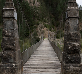 Obraz premium a stone pier, cable stay suspension foot bridge over a mountain river 