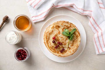 Stack of homemade pancakes served with honey and berries, top view