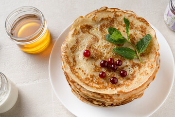 Stack of homemade pancakes served with honey and berries, top view