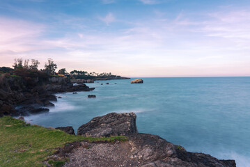 Beautiful long exposure scenic view of the rocky coastline in the Cantabrian sea on a cloudy day, Noja, Cantabria, Spain