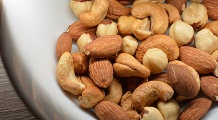 Healthy snack: Close up photo of roasted cashews, almonds and hazelnuts in a white bowl.	