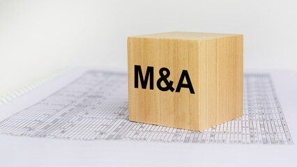 wooden block with letters M and A on white baclground. mergers and acquisitions concept