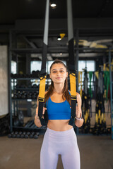 Fototapeta na wymiar Woman doing exercises with trx fitness straps in the gym