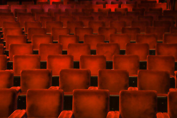 Red velvet chairs in a theater, highlighting the symmetry, lines and repetition of the seats.
