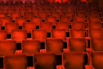 Red velvet chairs in a theater, highlighting the symmetry, lines and repetition of the seats.
