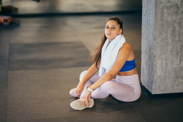 Naklejka premium Healthy young female sitting relaxed after training in gym.