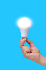 LED eco friendly light bulb in hand on blue background.