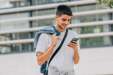 young man walking in the street looking at the mobile or cell phone