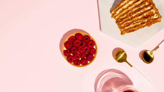 Raspberry tart and piece of honey cake on pink background. Stop Motion Animation. Space for text.