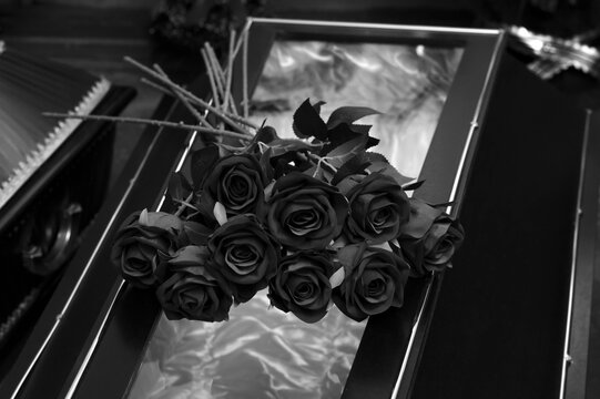 Wooden coffin indoors, decorated with a bouquet of roses, funeral home, black and white photo