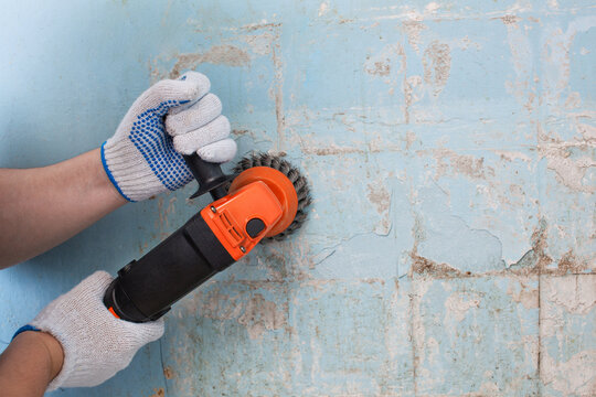 The builder holds in hands Angle grinder. Repair work, interior decoration of walls.